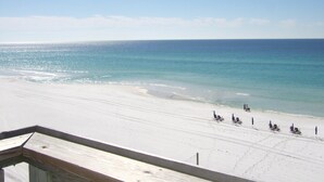 A beach with a clear view of the ocean and a wooden deck.