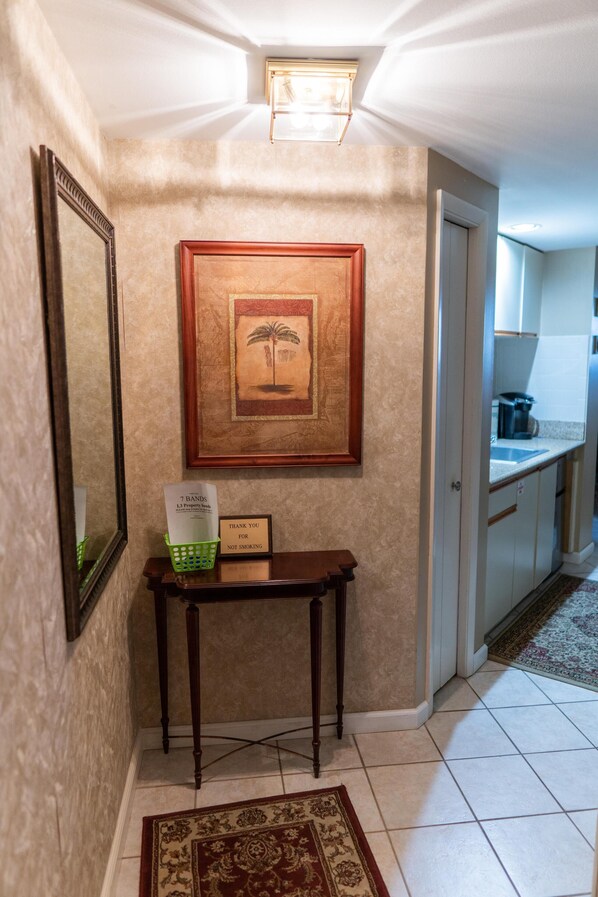 A hallway with a framed picture, a small table with a basket, and a sign. - Extra large studio condominium located at Surfside Resort (Miramar Beach)