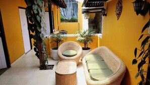 A yellow-walled room with wicker furniture, including a sofa, two chairs, and a small table.