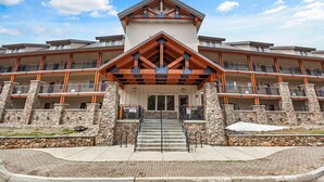 A multi-story hotel with a stone facade, wooden accents, and a central entrance with stairs.