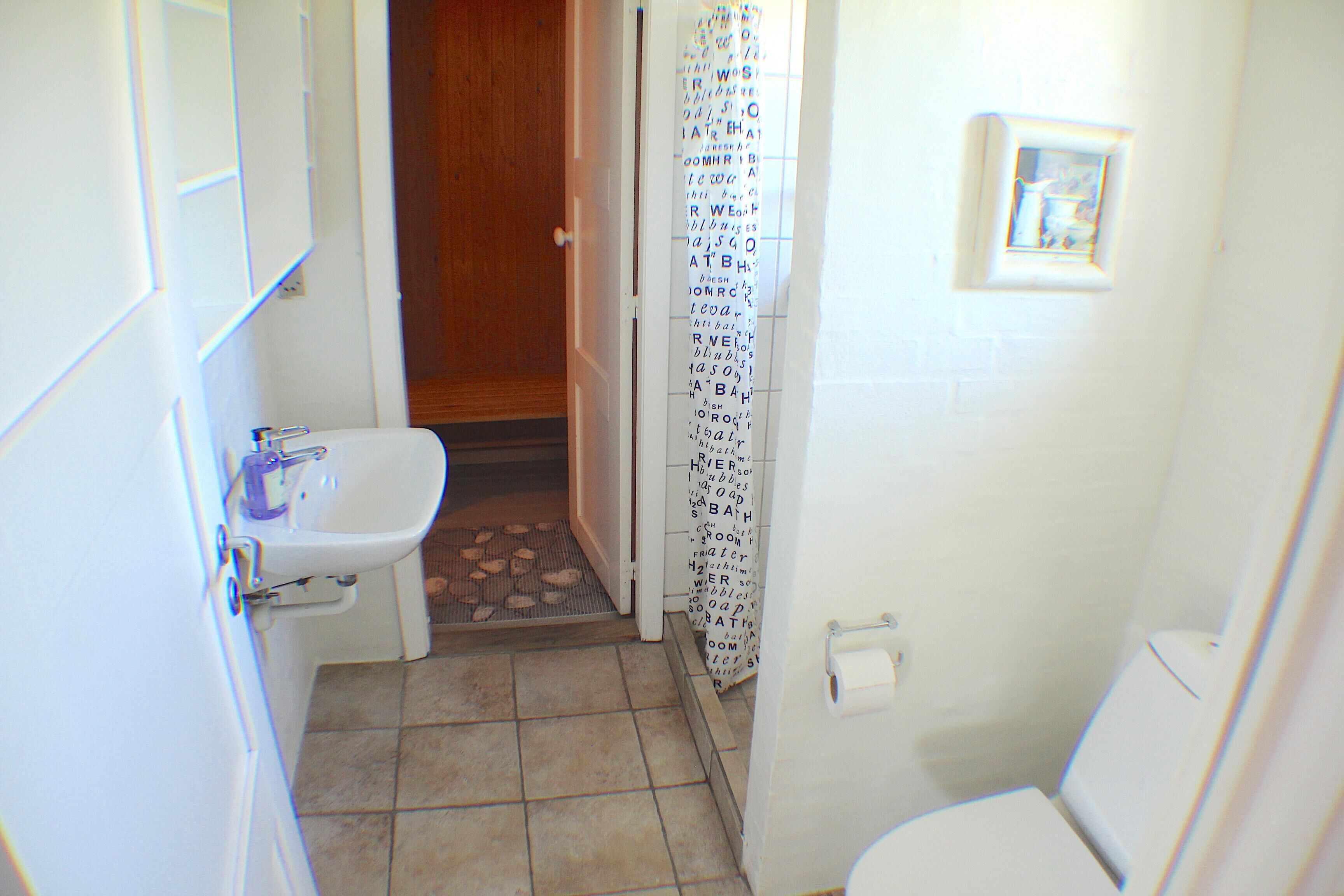 A small bathroom with a toilet, sink, and shower curtain.