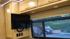 Une cuisine équipée d’un four à micro-ondes encastré et d’une fenêtre donnant sur une voiture garée et sur la verdure environnante.