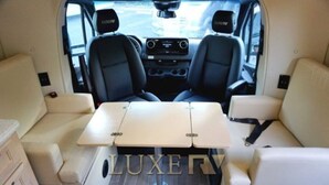 Un intérieur de luxe pour un véhicule récréatif, avec deux sièges en cuir noir, une table centrale et une inscription bien visible indiquant la marque « LUXERY ».