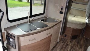 A compact kitchenette with two sinks, a built-in oven, and a small countertop.