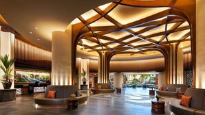 A spacious lobby with a modern design, featuring a curved ceiling with wooden beams and a seating area with sofas and a coffee table.