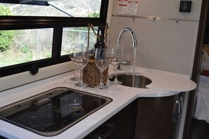 A kitchen with a sink, a window, and a wine bottle.