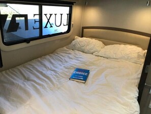 A bed with a book titled "Great Choice" by Jim Collins.