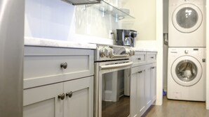 Una cocina moderna con electrodomésticos de acero inoxidable, armarios blancos y lavadora y secadora integradas.