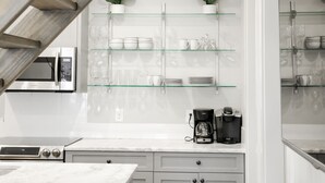 Una cocina moderna con una isla central, electrodomésticos de acero inoxidable y estantes de vidrio.