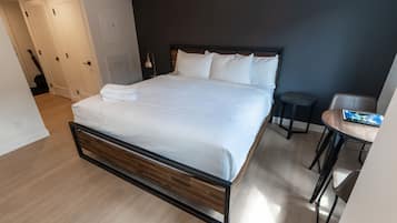 A modern hotel room with a large bed, a small round table, and a dark accent wall.