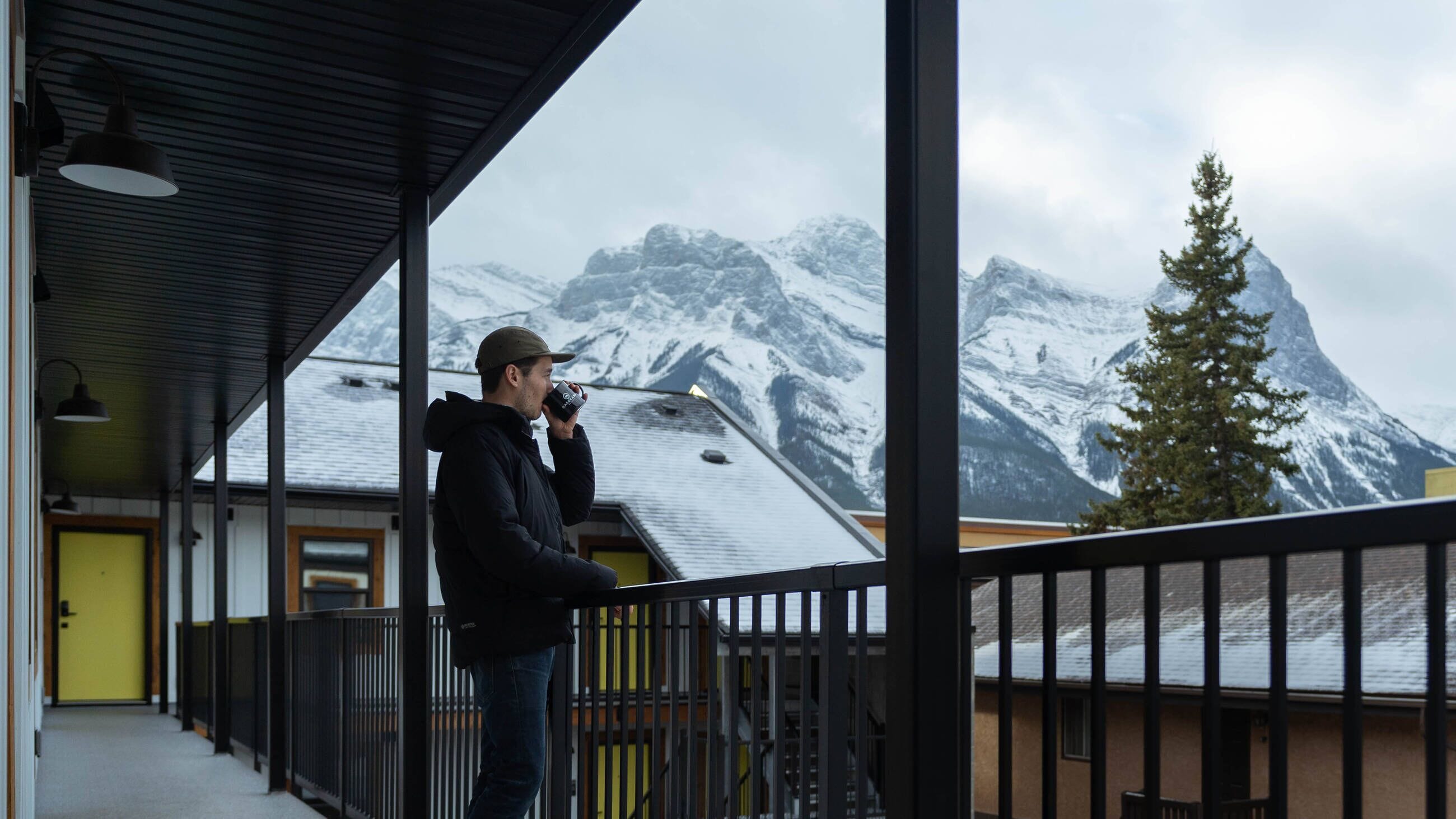 Una persona en un balcón con vistas a montañas nevadas.