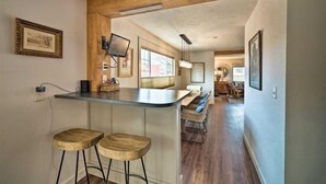Een keuken met een bar, houten krukken en een hangende lamp.