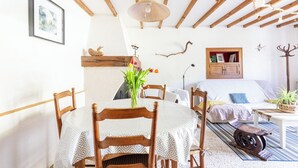 A cozy room with a wooden ceiling, a dining table with chairs, a bed with a white bedspread, and a small table with a plant. - Estuvi - La Sittelle Enchantée, a break in the countryside. bike shelter, animals ok  (CHEMENOT)