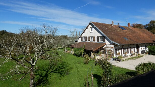 A two-story house with a sloped roof, a small attached garage, and a visible chimney. - Estuvi - La Sittelle Enchantée, a break in the countryside. bike shelter, animals ok  (CHEMENOT)