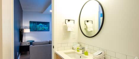 A modern bathroom with a large mirror, a sink, and a towel rack.