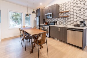 Una cocina moderna con una mesa de comedor de madera, armarios oscuros y un salpicadero geométrico.