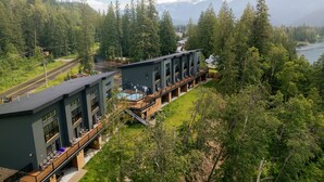 A modern hotel with a pool, outdoor seating, and a view of mountains and a lake. - Basecamp Resorts Revelstoke (Revelstoke)
