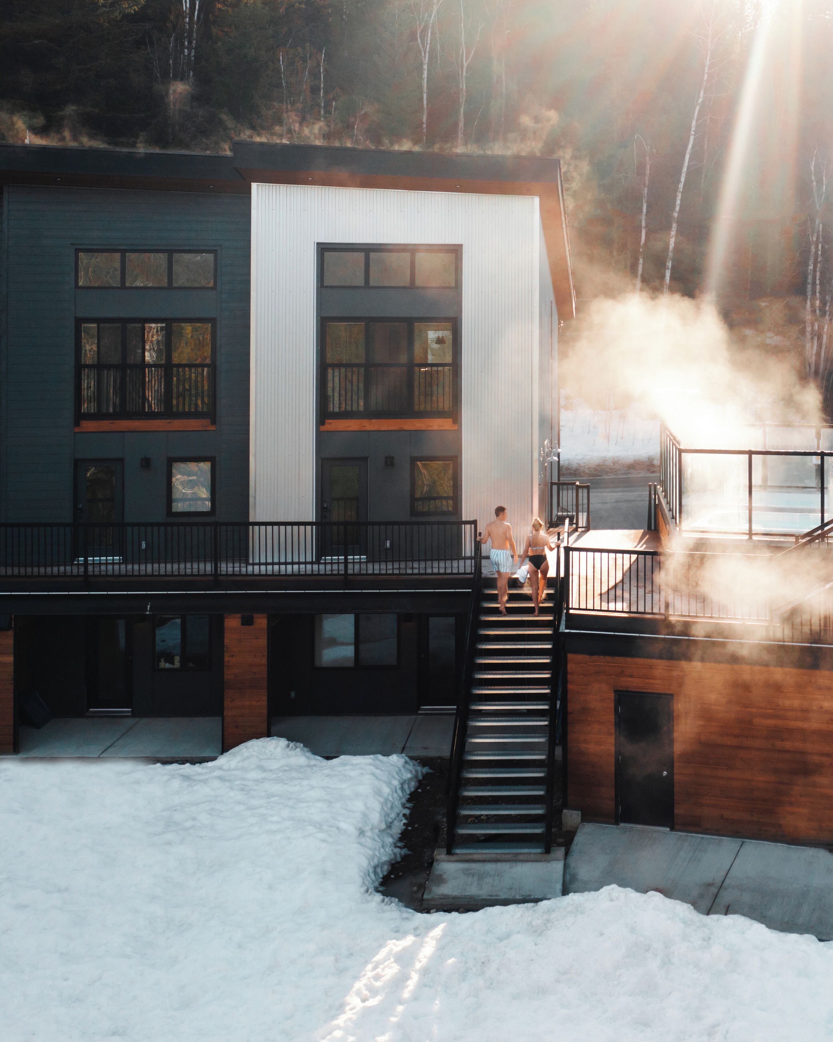 A modern building with a staircase leading to a deck, surrounded by snow.