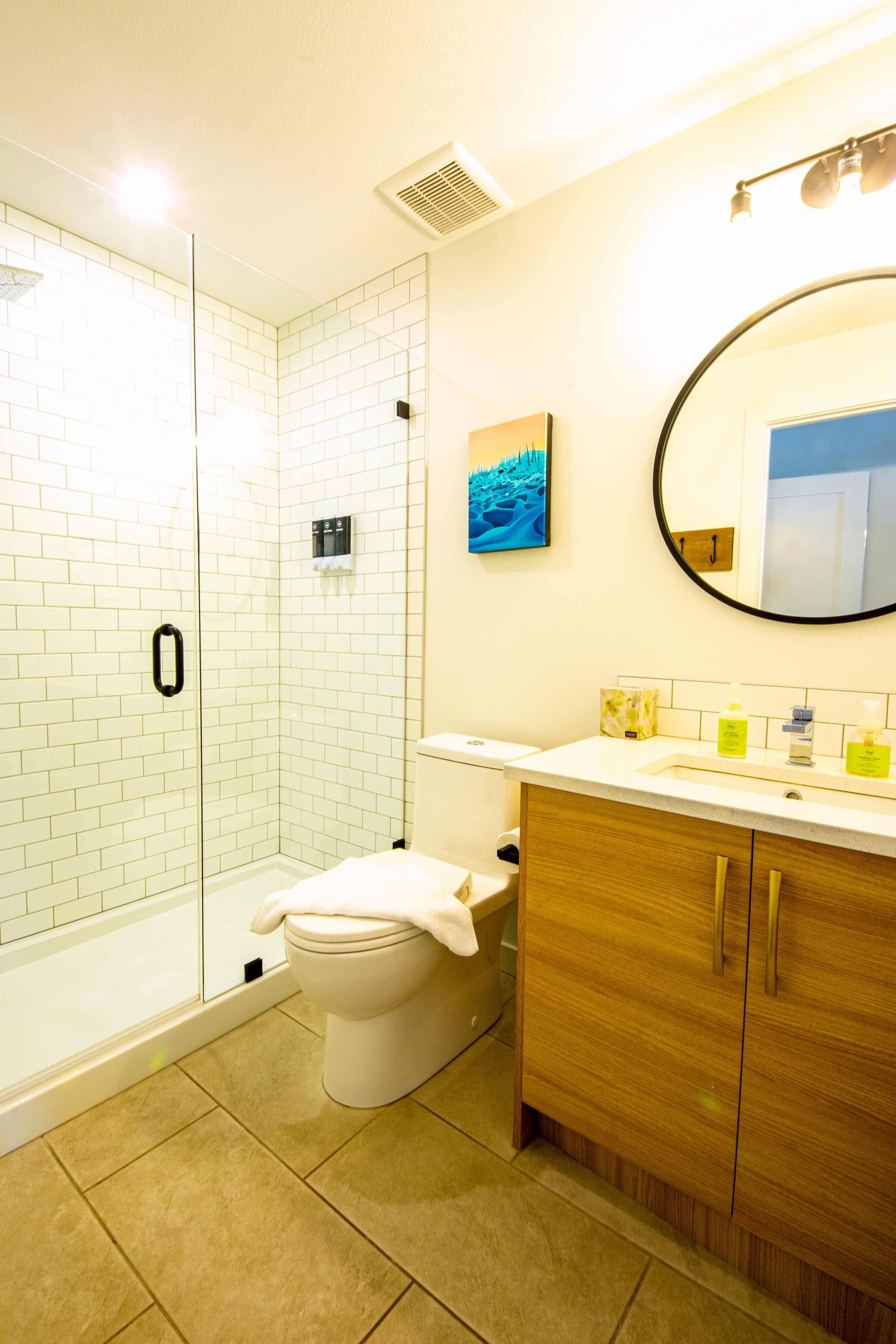 Un baño con ducha de vidrio, inodoro, lavabo con espejo y armario de madera.