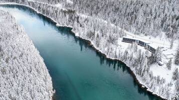 An aerial view of a snow-covered river with a building adjacent to it.