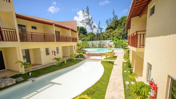 Un complexe hôtelier doté d’une piscine, de nombreux balcons et d’un aménagement paysager luxuriant.