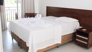 Une chambre d’hôtel avec un lit en bois, du linge de lit blanc, une table de chevet en bois et une vue sur l’extérieur.