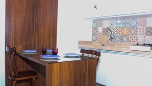 Une table de salle à manger en bois avec des chaises, un pare-feu en carreaux et un évier de cuisine.
