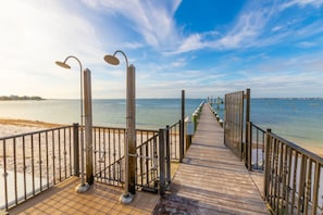 Walk along the boardwalk to the serene beach, where the calm waters meet the distant shoreline.