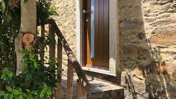 Ein Steinhaus mit einer Holztür und Stufen, die zu einem Fenster führen.