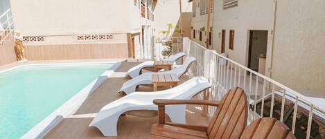 A poolside area with lounge chairs and umbrellas.