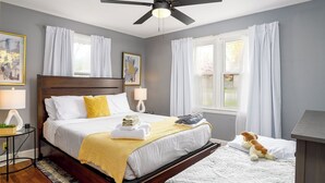 A neatly arranged bedroom with a bed, bedside tables, a ceiling fan, and a window with curtains. - Market 6min, HPU 2Min, Private Patio, Downtown 5min, Dogs Ok, 3 SMART TVs (High Point)