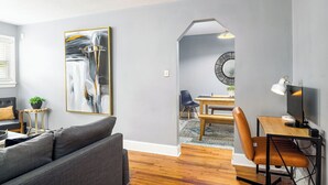 A modern living room with a grey sofa, a dining area with a wooden table and chairs, and a large abstract painting on the wall. - Market 6min, HPU 2Min, Private Patio, Downtown 5min, Dogs Ok, 3 SMART TVs (High Point)