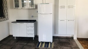 Eine kleine Küche mit weißen Schränken, einer schwarzen Arbeitsplatte und einem Kühlschrank.