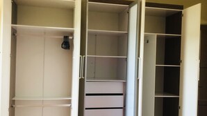 Ein begehbarer Kleiderschrank mit geöffneten Türen, der zahlreiche Regale und Schubladen zeigt.