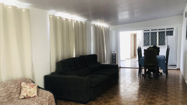 Ein Wohnzimmer mit einer Couch, einem gemusterten Sessel, einem Esstisch mit Stühlen und einem Teppich mit Muster.