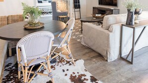Un salon moderne comprenant un coin repas, un tapis en peau de vache et un lustre.