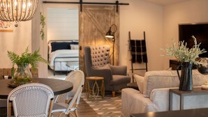 Un salon moderne comprenant un coin repas, un canapé capitonné et un lustre.