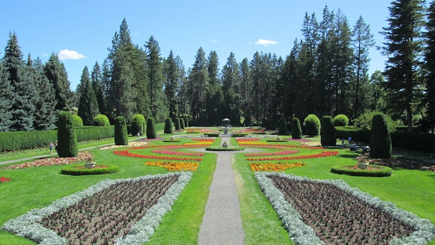 Ein formaler Garten mit symmetrischen Blumenbeeten, einem zentralen Weg und ordentlich geschnittenen Hecken.