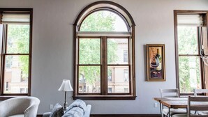 Una habitación con un ventanal arqueado grande, un sofá, una mesa y una lámpara.