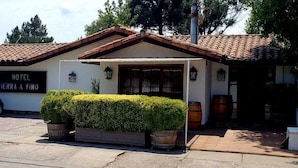 A hotel named "TIERRA & VINO" with a car parked in front, a well-maintained hedge, and a traditional tiled roof. - Tierra y Vino (Santa Cruz)