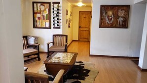 A room with a wooden floor, a glass-top table, a chair, and a rug. - Tierra y Vino (Santa Cruz)