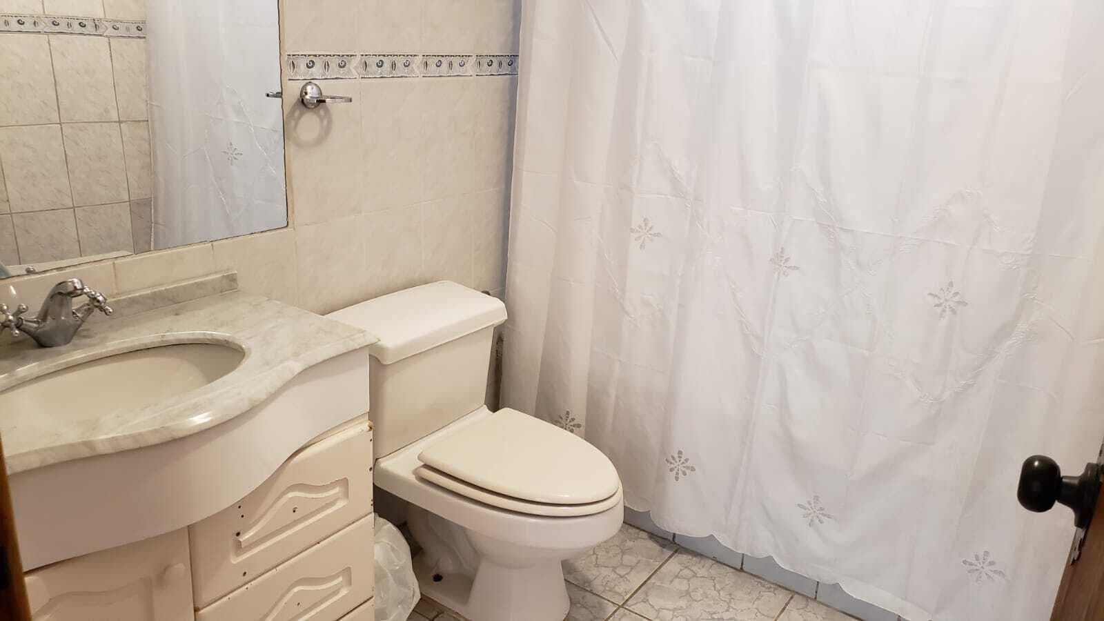 Un baño con lavamanos, inodoro y cortina de ducha blancos.