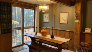 Un tavolo da pranzo in legno con un centrotavola a forma di zucca, opere d'arte appese alle pareti e una panca in legno.