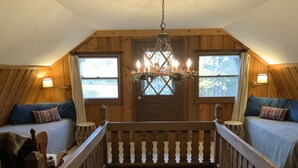 Una camera accogliente con due letti, un lampadario e pareti in legno.