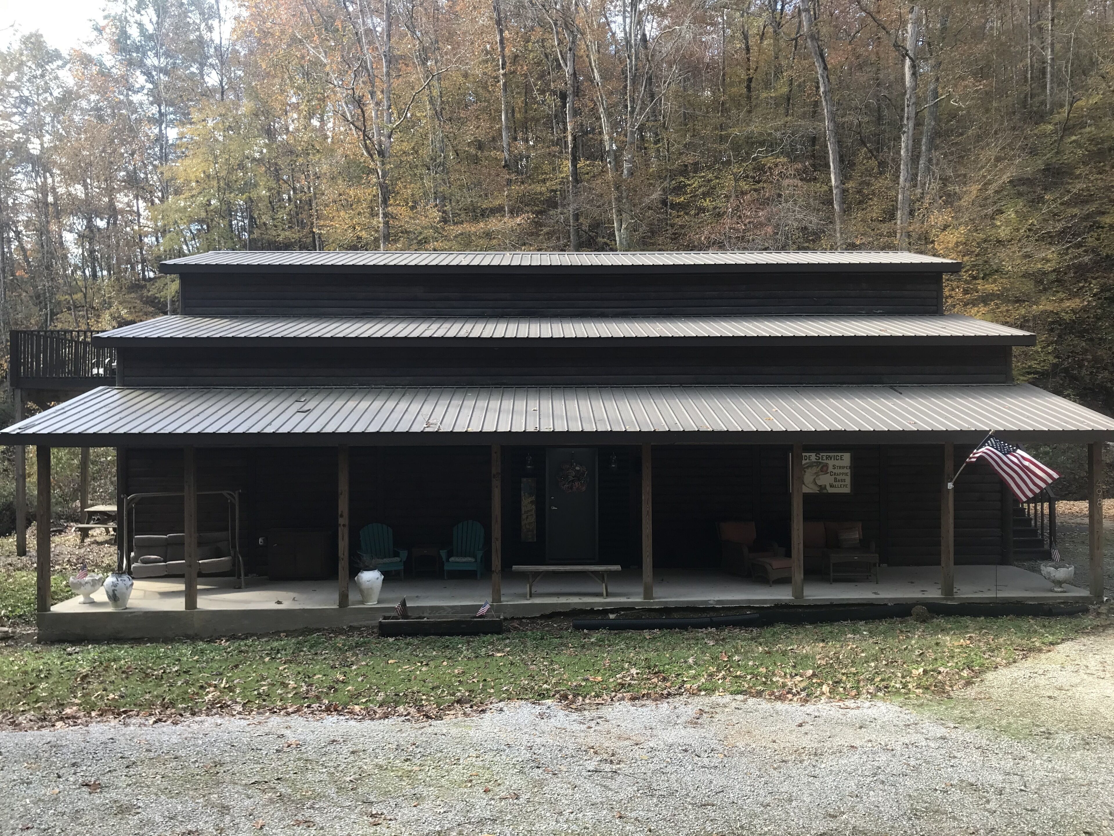 Une cabane à deux étages avec un porche, un drapeau et une pancarte indiquant que des services sont offerts aux clients.