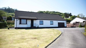 A single-story house with a tiled roof, a front porch, and a driveway leading to a garage. - Glendaruel Bed & Breakfast (Portree)