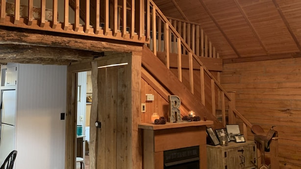 Un intérieur rustique avec un escalier en bois, une cheminée et un ventilateur de plafond.