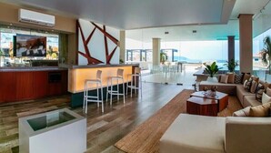 Een moderne hotellobby met een bar, zitplaatsen en uitzicht op zee.