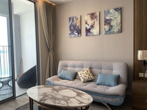 Un salon moderne avec un canapé, une table basse en marbre et des œuvres d’art abstraites accrochées au mur.