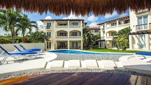 A resort with a swimming pool, lounge chairs, and a thatched roof structure. - Great 1BR Condo w/ Pool, Near Beach! AC! (Playa Del Carmen)
